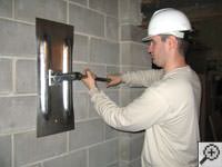Attempting to straighten a bowed foundation wall by straightening a wall anchor system in a Hockessin home.