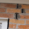 A brick wall displaying stair-step cracks and messy tuckpointing on a Chester home