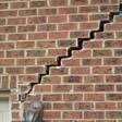 stair step cracking reaching from a window along the foundation wall in Dover